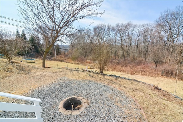 view of yard with a fire pit and a trampoline