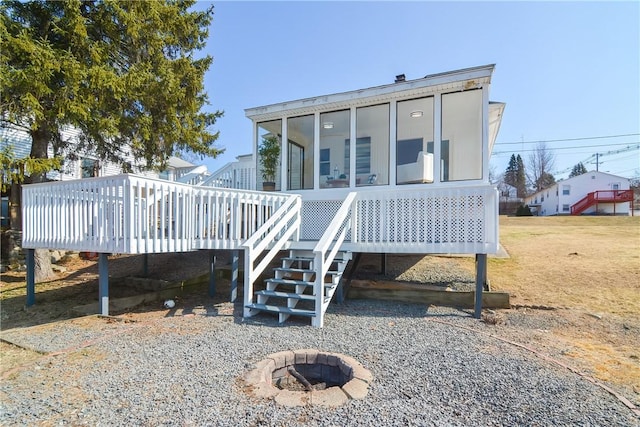 back of property featuring stairway, a fire pit, a wooden deck, and a sunroom