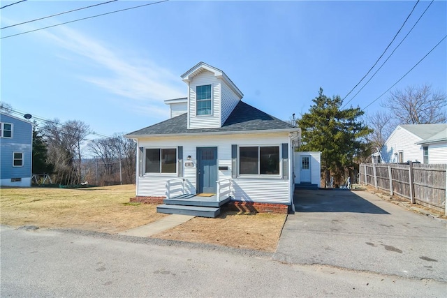 view of front of home with a front yard, fence, and roof with shingles