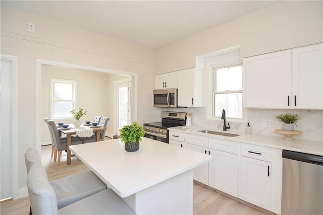 kitchen with a sink, light countertops, white cabinets, and stainless steel appliances