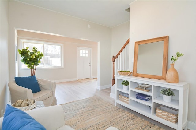 living area featuring stairway, light wood-style flooring, and baseboards