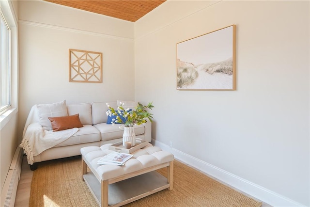 living room with baseboard heating, wooden ceiling, baseboards, and wood finished floors