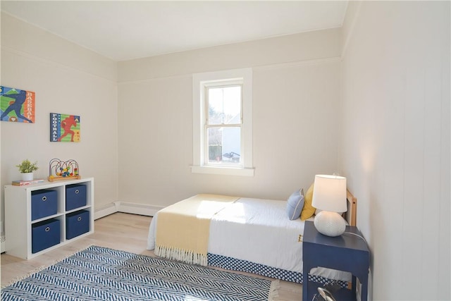 bedroom with light wood finished floors and a baseboard radiator