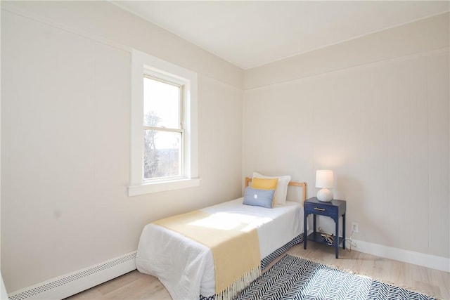 bedroom featuring a baseboard heating unit, baseboards, and wood finished floors