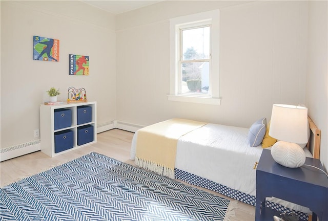 bedroom with light wood-style flooring and a baseboard heating unit