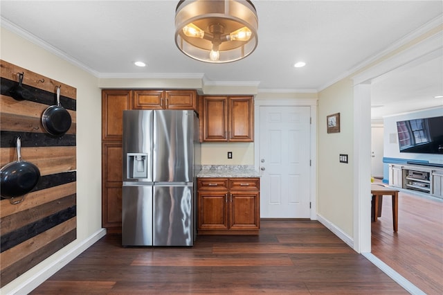 kitchen featuring dark wood-type flooring, ornamental molding, stainless steel fridge, and brown cabinets