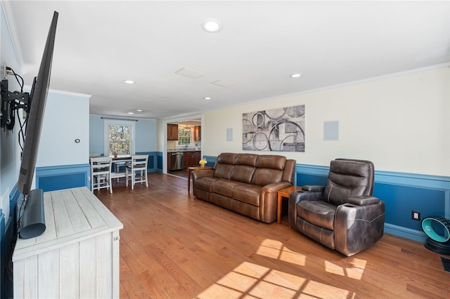 living area with light wood finished floors, recessed lighting, wainscoting, and crown molding