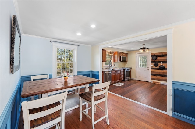 dining room with recessed lighting, dark wood-type flooring, wainscoting, and crown molding