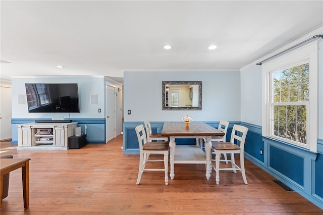 dining space with visible vents, recessed lighting, light wood-style floors, and a wainscoted wall