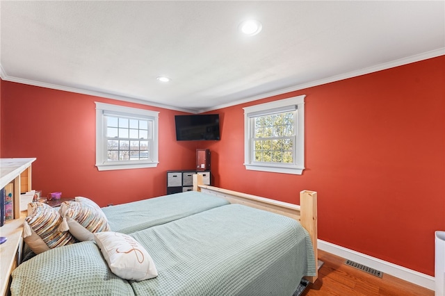 bedroom featuring wood finished floors, baseboards, visible vents, recessed lighting, and ornamental molding