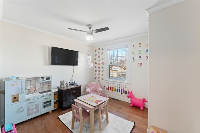 rec room with visible vents, ornamental molding, a ceiling fan, and wood finished floors