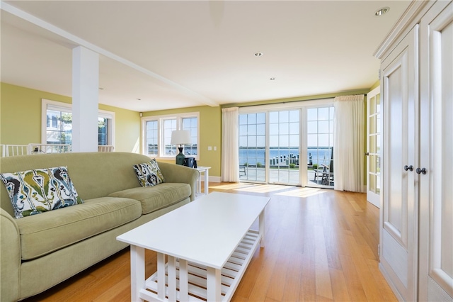 living area with light wood-style flooring and a water view