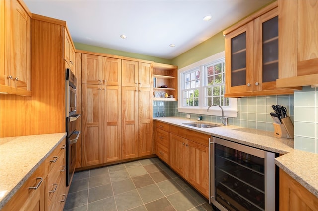 kitchen with a sink, light stone counters, tasteful backsplash, wine cooler, and stainless steel oven