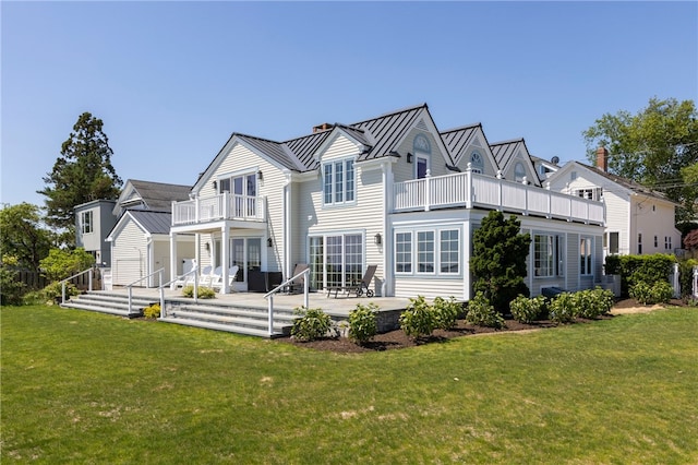 rear view of property featuring a yard, a balcony, metal roof, and a standing seam roof