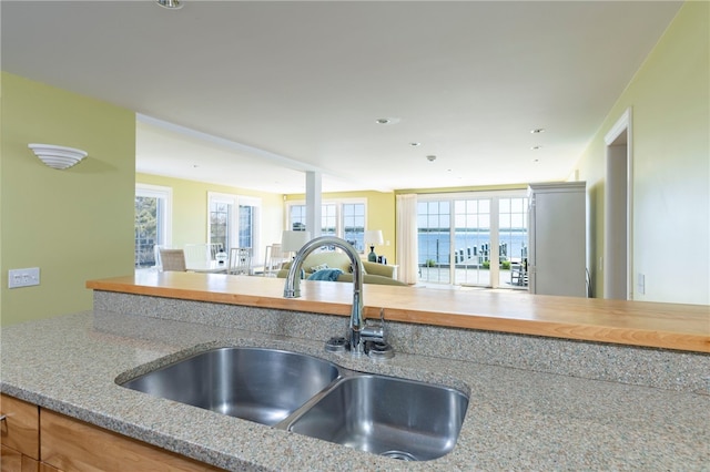 kitchen with light stone countertops, open floor plan, and a sink