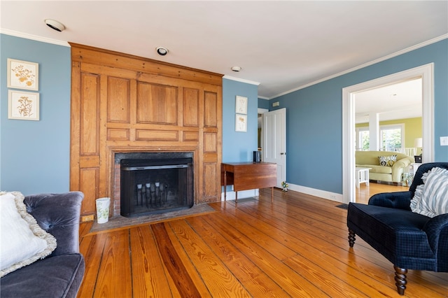 living room with wood finished floors, crown molding, a fireplace, and baseboards