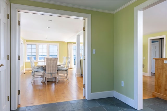 corridor with crown molding, baseboards, and dark wood-style flooring