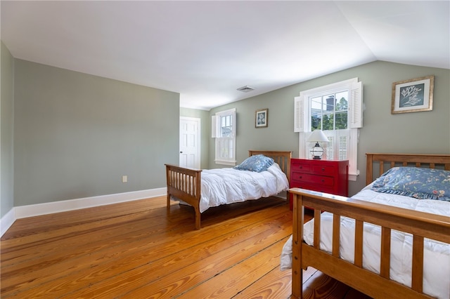 bedroom featuring vaulted ceiling, baseboards, visible vents, and light wood-type flooring