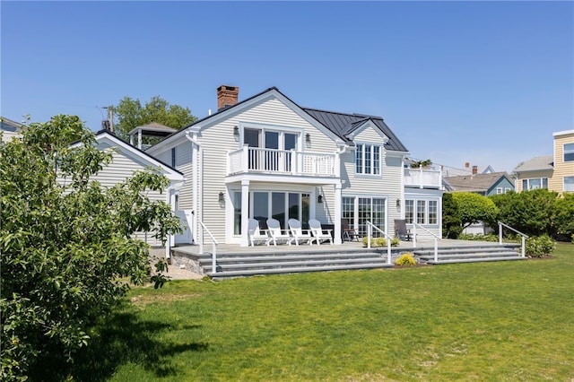 rear view of property featuring a patio, a balcony, a lawn, and a chimney