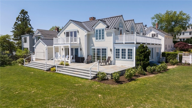 back of property featuring a lawn, a standing seam roof, metal roof, a balcony, and a chimney