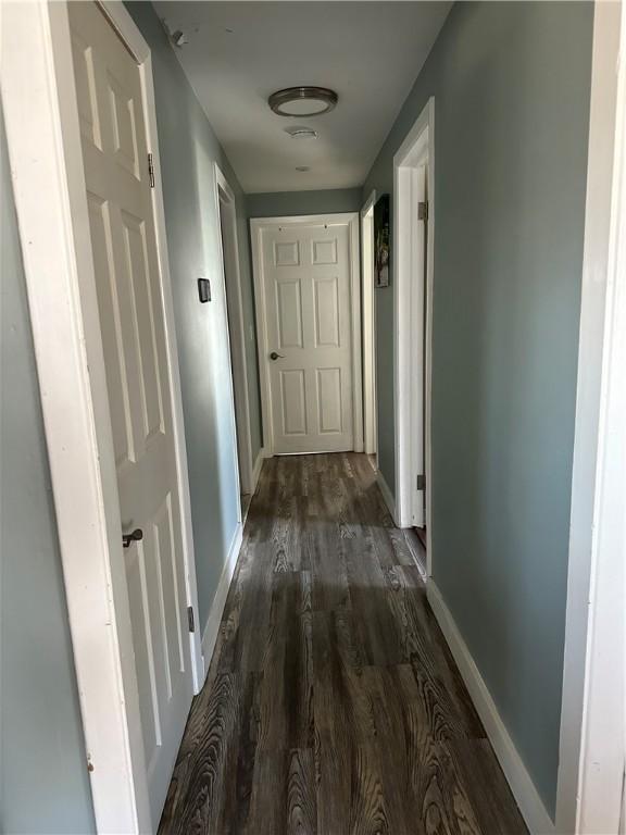 corridor featuring dark wood finished floors and baseboards