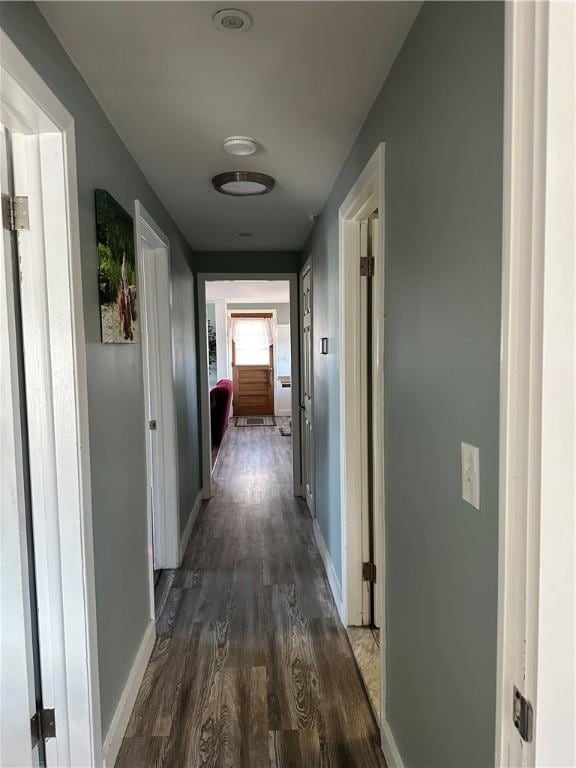 hallway featuring baseboards and dark wood finished floors