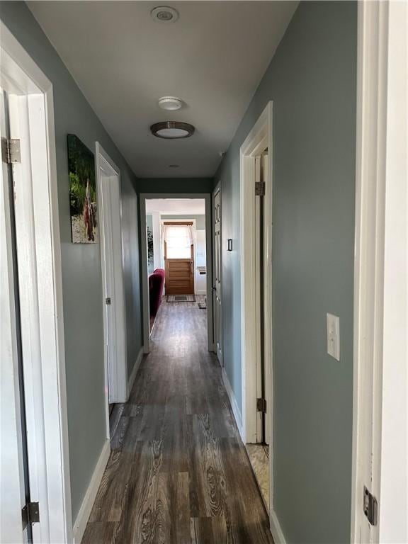 hall featuring dark wood-style flooring and baseboards