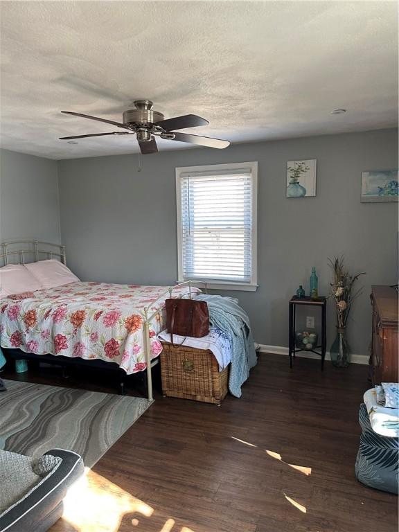 bedroom featuring baseboards, a textured ceiling, wood finished floors, and a ceiling fan