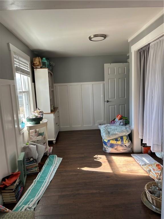 interior space featuring a decorative wall, wainscoting, white cabinets, and dark wood-style flooring