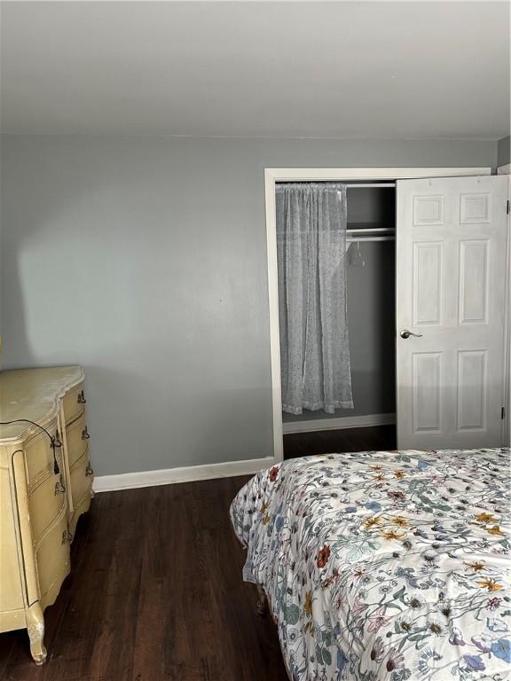 bedroom featuring dark wood finished floors, baseboards, and a closet