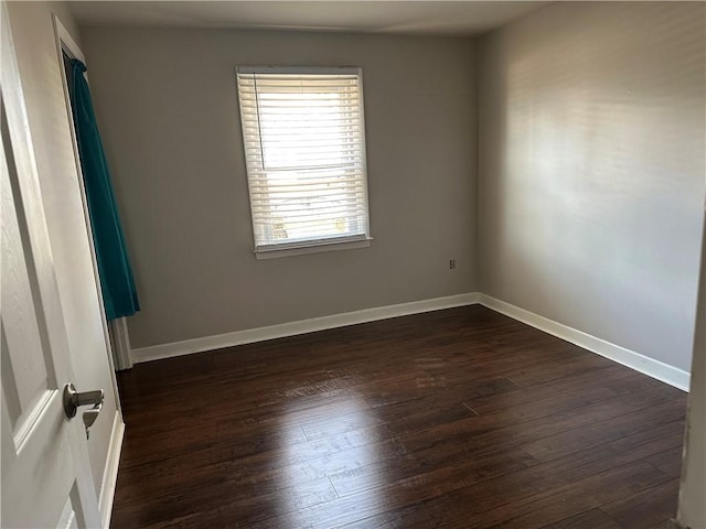 empty room with baseboards and dark wood-type flooring