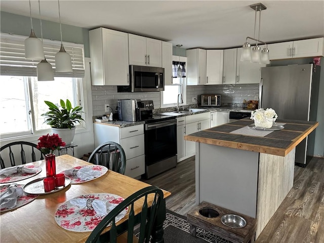 kitchen featuring white cabinets, dark wood-style flooring, a sink, stainless steel appliances, and decorative backsplash