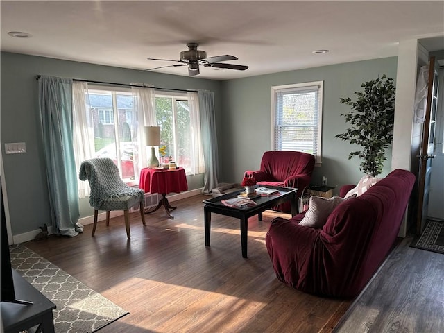 living area featuring dark wood-style floors, baseboards, and a ceiling fan