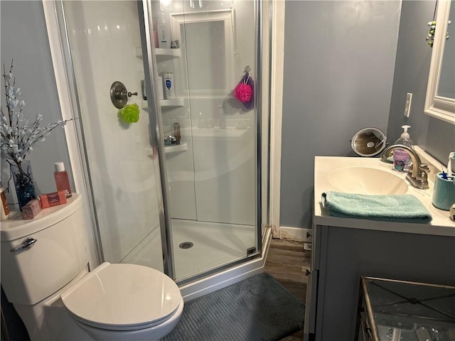 bathroom with toilet, a stall shower, wood finished floors, and vanity