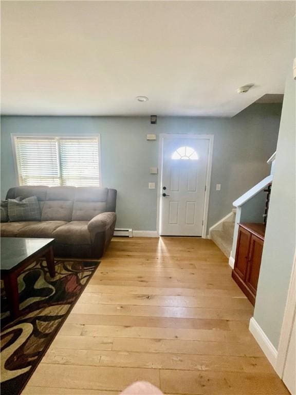 foyer entrance featuring stairway, baseboards, light wood-type flooring, and a baseboard radiator