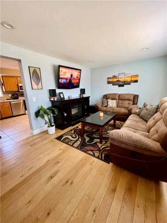 living area with light wood-type flooring, baseboards, and a fireplace