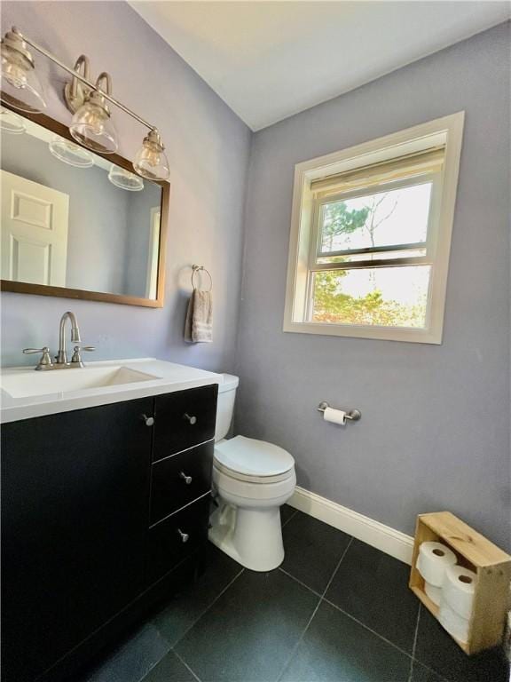 half bathroom with tile patterned flooring, toilet, vanity, and baseboards