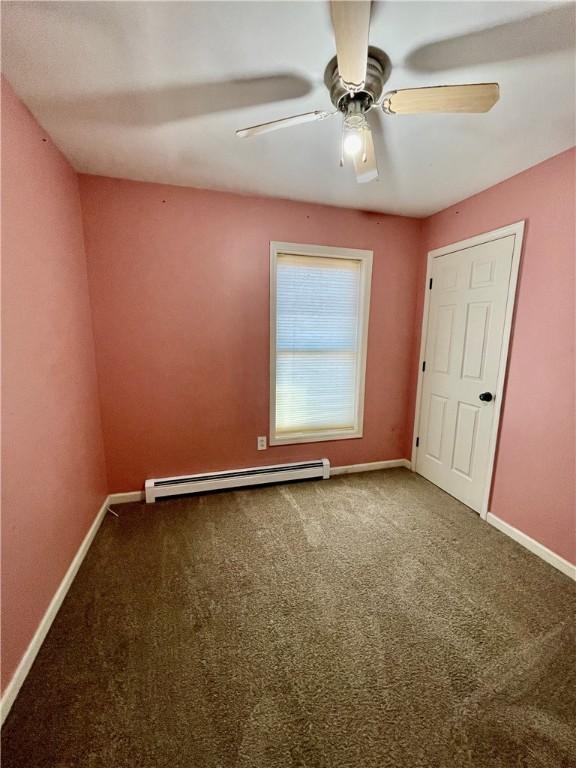 unfurnished bedroom featuring a ceiling fan, baseboards, baseboard heating, and carpet floors