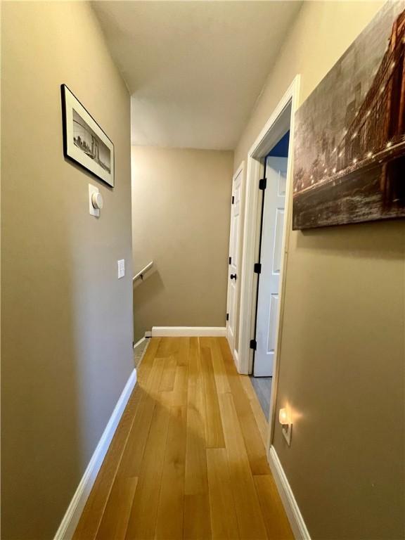 hall with baseboards and wood-type flooring