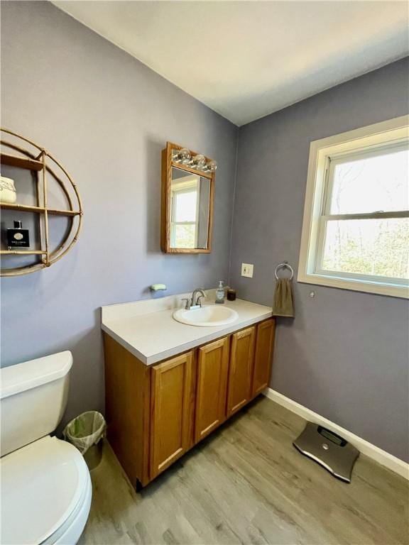 bathroom with baseboards, toilet, wood finished floors, and vanity