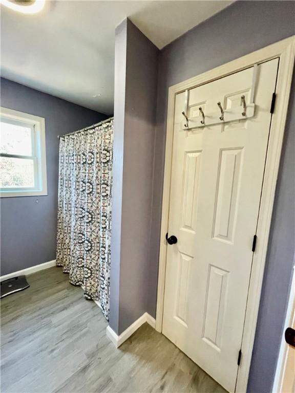 full bath featuring baseboards, a shower with curtain, and wood finished floors