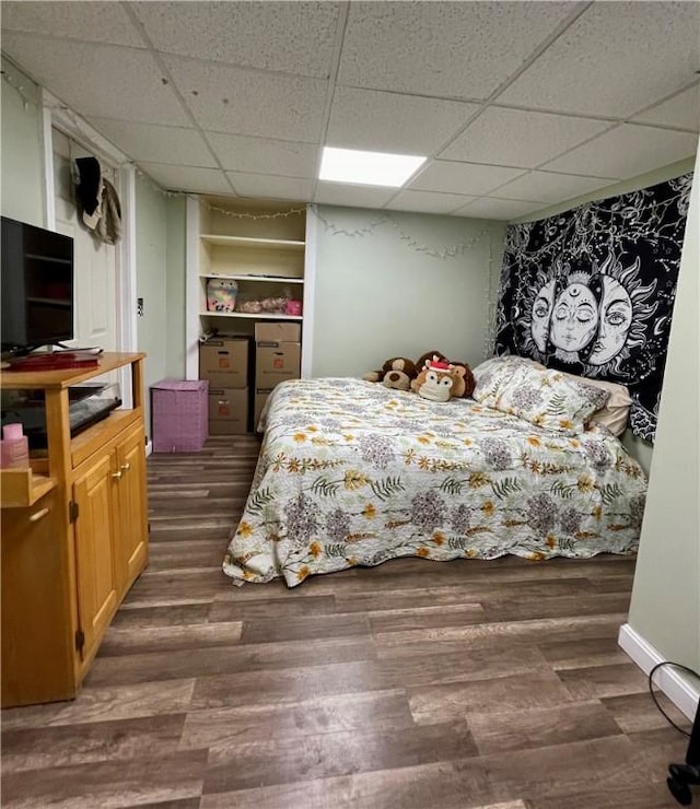 bedroom featuring dark wood finished floors and a drop ceiling