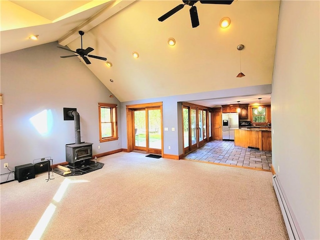 unfurnished living room featuring a wood stove, light carpet, baseboard heating, and a ceiling fan