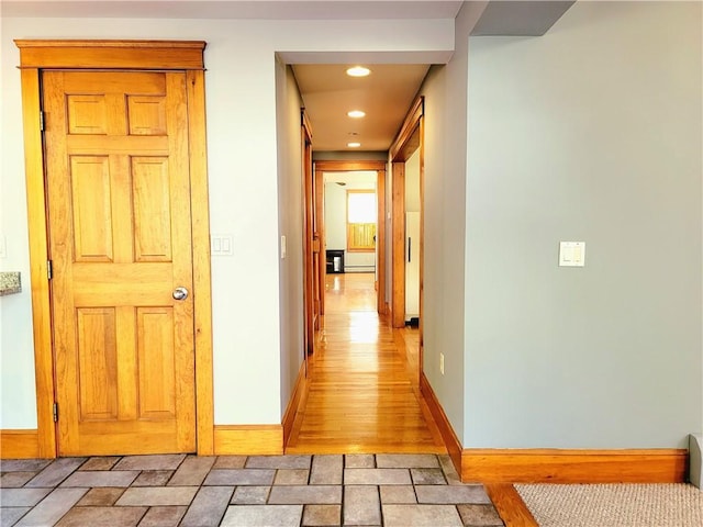 hallway with recessed lighting, stone finish flooring, and baseboards