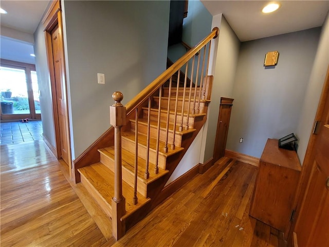 stairway featuring baseboards and hardwood / wood-style floors