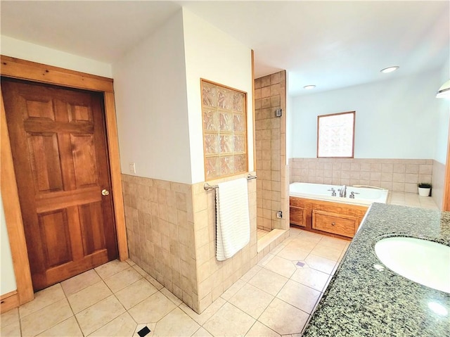 bathroom with tile patterned flooring, tile walls, a shower stall, and a sink