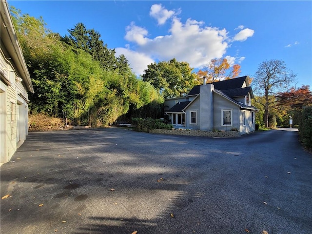 view of home's exterior featuring aphalt driveway and a chimney