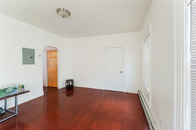 empty room with a baseboard heating unit, electric panel, wood finished floors, and arched walkways