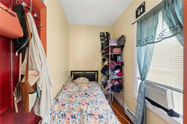 bedroom featuring wood finished floors, baseboards, and a baseboard radiator