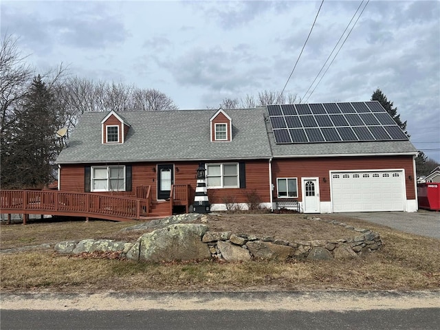 view of front of home featuring solar panels, a shingled roof, aphalt driveway, a wooden deck, and a garage